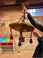 Full view of brass fixture held upright, showing stem, canopy, dish, and four hanging sockets