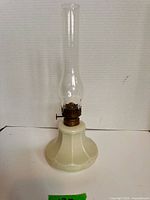 Full view of lamp showing milk glass base, brass burner, clear chimney