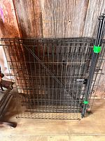 Stacked black wire fence panels with gate section visible