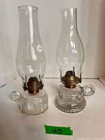 Both clear pressed glass finger oil lamps with chimneys side by side