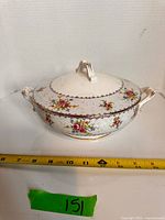 Top view of covered vegetable dish showing pattern, handles, and measuring tape