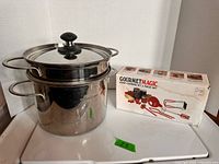 Pasta pot with lid, strainer insert stacked inside, box of Gourmet Magic canning kit beside