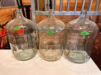 Front view of three identical clear glass carboys on table