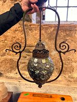 Full view of hanging fixture showing metal frame and stained glass shade