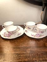 Four pieces: two teacups, two snack plates displayed on wooden surface