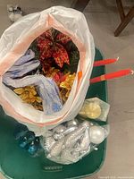 Overview of open bin showing bag of poinsettias, ribbons and ornament bags