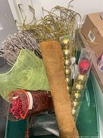Overall view of tote and contents including coco coir roll, green ribbon, twig sprays, ornament tubes