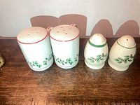 Four ceramic holiday salt and pepper shakers, two cylindrical with red rims and two Spode egg-shaped with green rims