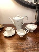 Teapot, teacup on saucer, creamer, lidded sugar bowl showing pattern and gold trim