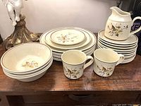 Full set of plates, bowls, cups and creamer jug arranged on table