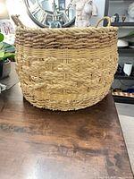 Full view of seagrass basket on table showing shape, weave, and handles
