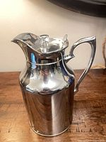 Front view of stainless steel insulated pitcher with handle and lid