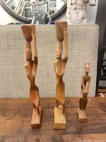 Group view of all three wooden figurines standing on table