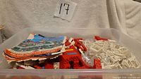 Plastic storage bin holding numerous red and white Halsam bricks and white specialty pieces, instruction booklet visible