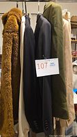 Six garments hanging: brown faux fur jacket, cream blazer, black blazer, charcoal pinstripe blazer, olive coat, beige coat