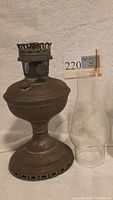 Oil lamp base with glass chimney shade beside it