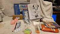 Overall view of lot on table showing keychain, Staedtler sets, markers, canvas, bells and assorted items