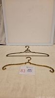 Two brass hangers on cloth backdrop