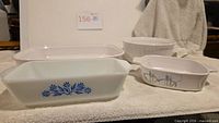 Group view of four vintage baking dishes: rectangular French White baker, round French White baker, Shadow Iris casserole and Fire-King Blue Cornflower loaf pan