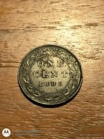 Reverse of 1893 Canada one-cent coin on wood surface