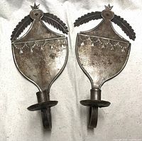 Front view of both tin sconces showing backplates, arms and candle cups