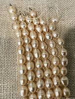 Close view multiple cream-peach oval pearls on thread