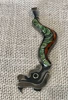 Front view of silver Quetzalcoatl pendant showing green malachite and brown stone inlays