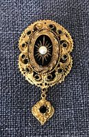 Front view of brooch showing enamel centre, faux pearl, rhinestones and dangle