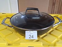 Wok with glass lid displayed on yellow surface