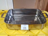 Rectangular stainless steel roasting pan with rack inside and side handles visible