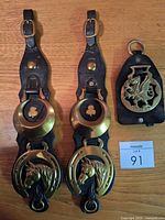 Two long leather straps with brass clover and horse-head medallions plus one short strap with Welsh dragon brass
