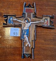 Front view of tooled leather crucifix showing painted figures and overall condition