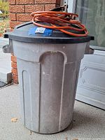 Trash can with lid and coiled booster cables on top