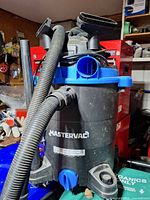Front view of Mastervac wet/dry vacuum with hose and attachments visible