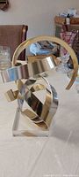 Front view of aluminum ribbon sculpture on lucite base