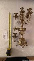 Full view of candelabra beside tape measure, detached pieces shown