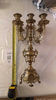 Full view of brass five-arm candelabra beside tape measure showing ~19 in height