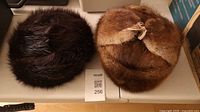 Both fur Ushanka hats side by side on table