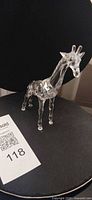 Front left view of clear faceted crystal baby giraffe figurine standing on four legs, shows frosted mane and ossicones