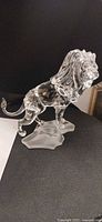 Full right-side profile of clear crystal lion on frosted base