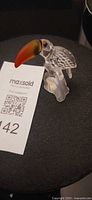 Front view of Swarovski crystal toucan figurine showing orange-red beak and clear faceted body