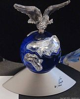 Front view of sapphire blue crystal globe with clear continents, dove, and silver-tone base