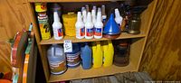 Cabinet shelf with assorted automotive and garden chemical bottles, funnels, metal oilers