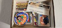 Box containing assorted loose cards, promo disc, Joe Montana card visible