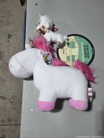 Large Fluffy Unicorn plush and smaller Lucky goat plush on table