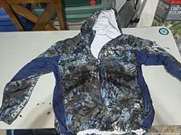 Front view of Huk camouflage fishing jacket with hood displayed