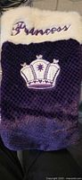 Front view showing Princess embroidery on white faux fur cuff and crown motif on purple body