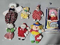 Group shot of six loose dolls and boxed porcelain clown
