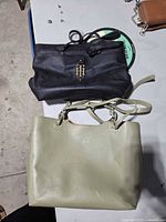 Black Tommy Hilfiger handbag and sage green Pixie Mood tote on table