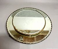 Oblique view of both mirrors stacked, showing beaded rims and feet